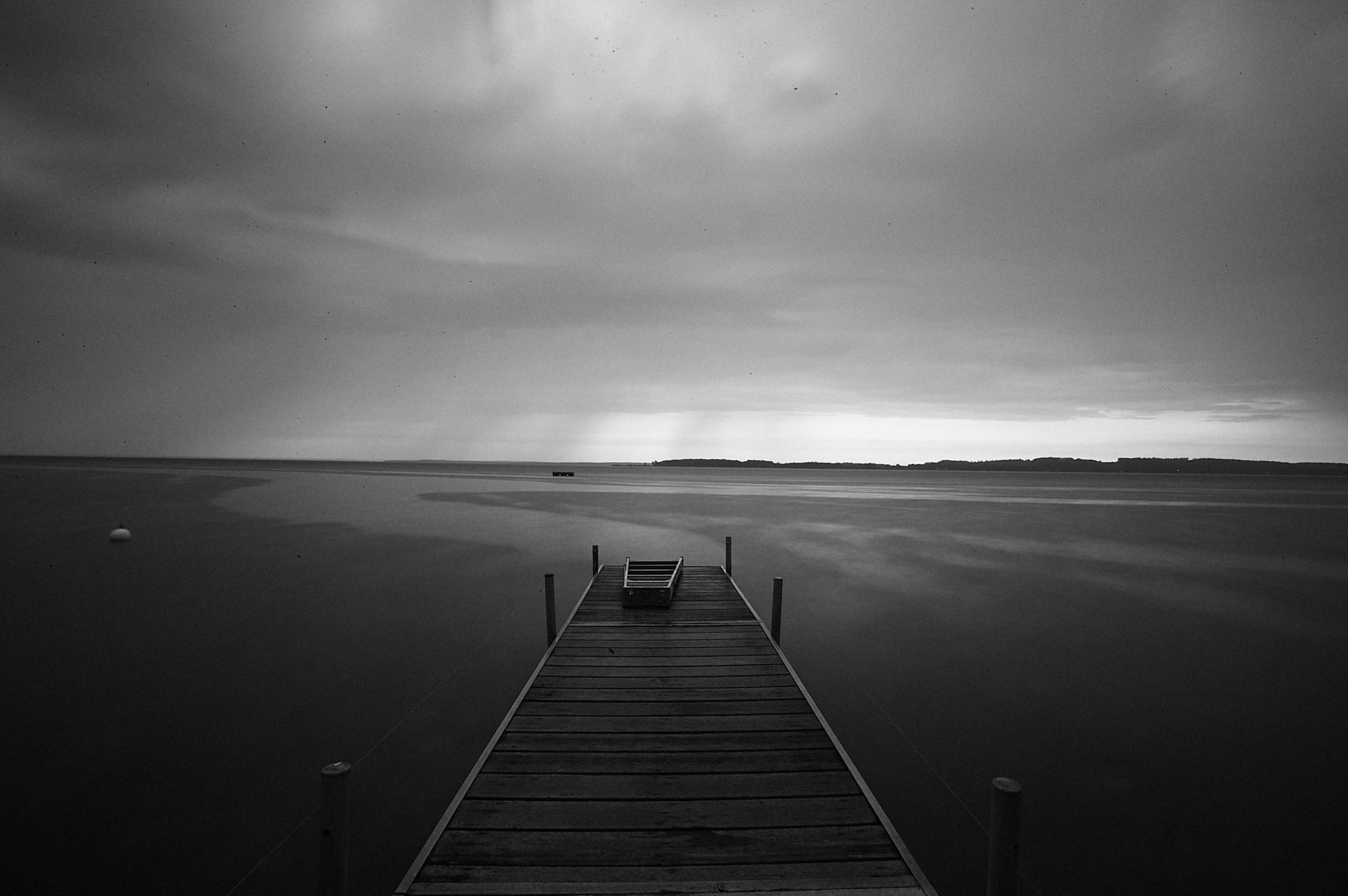 dock leading into the water of Suttons Bay Michigan as a rainstorm approaches